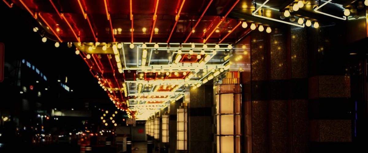 Dim casino tournament floor lit by warm gold stage lighting.